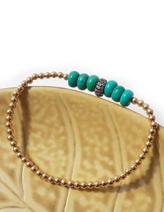 Armband mit runden goldenen und türkisfarbenen Perlen.